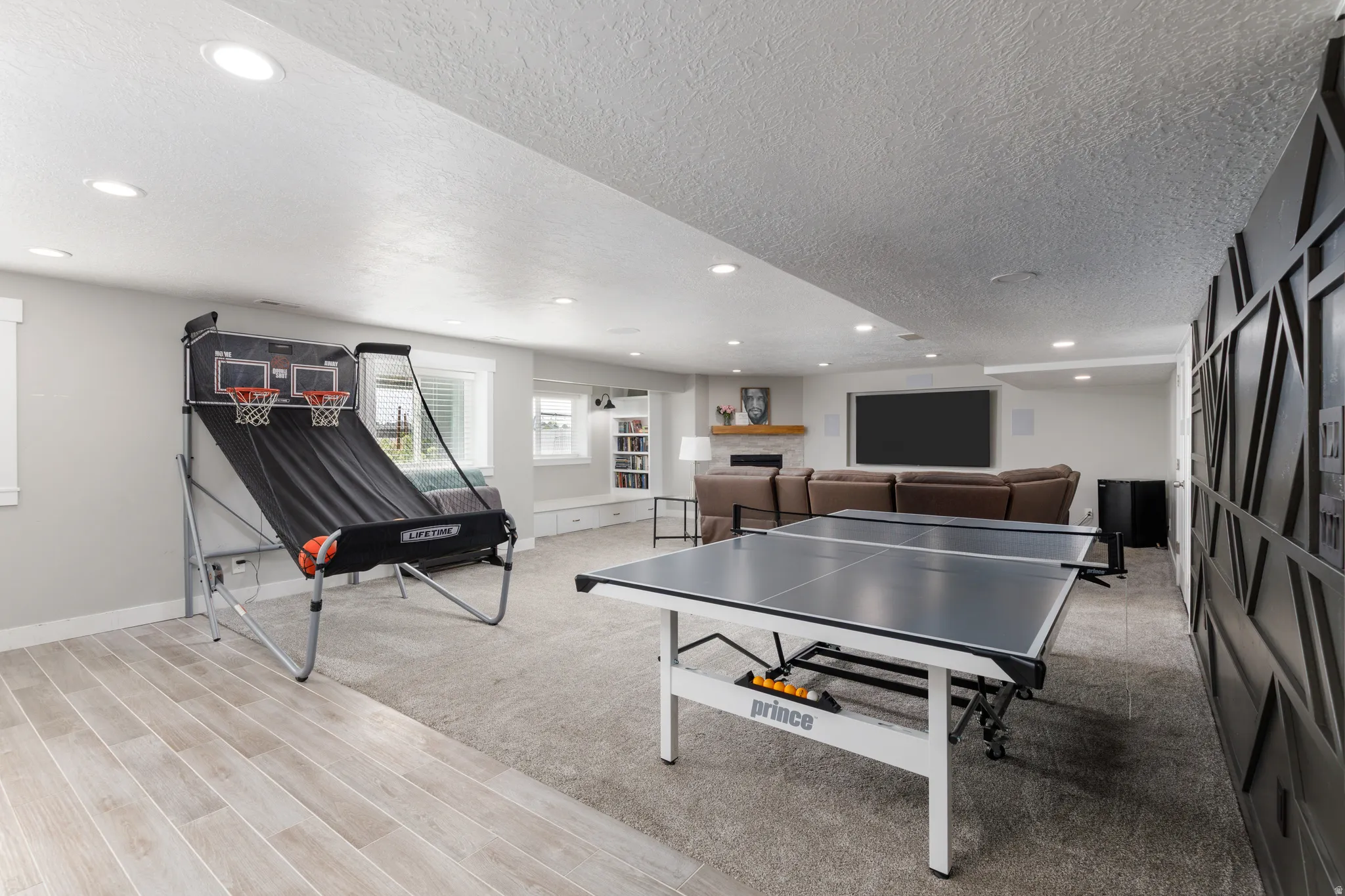 Spacious open-concept lower level featuring recessed lighting, a built-in entertainment area, multiple windows, and a combination of carpet and wood-finish flooring