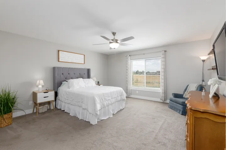 Neutral toned walls with carpet flooring, a ceiling fan with integrated lighting, and a window with blinds