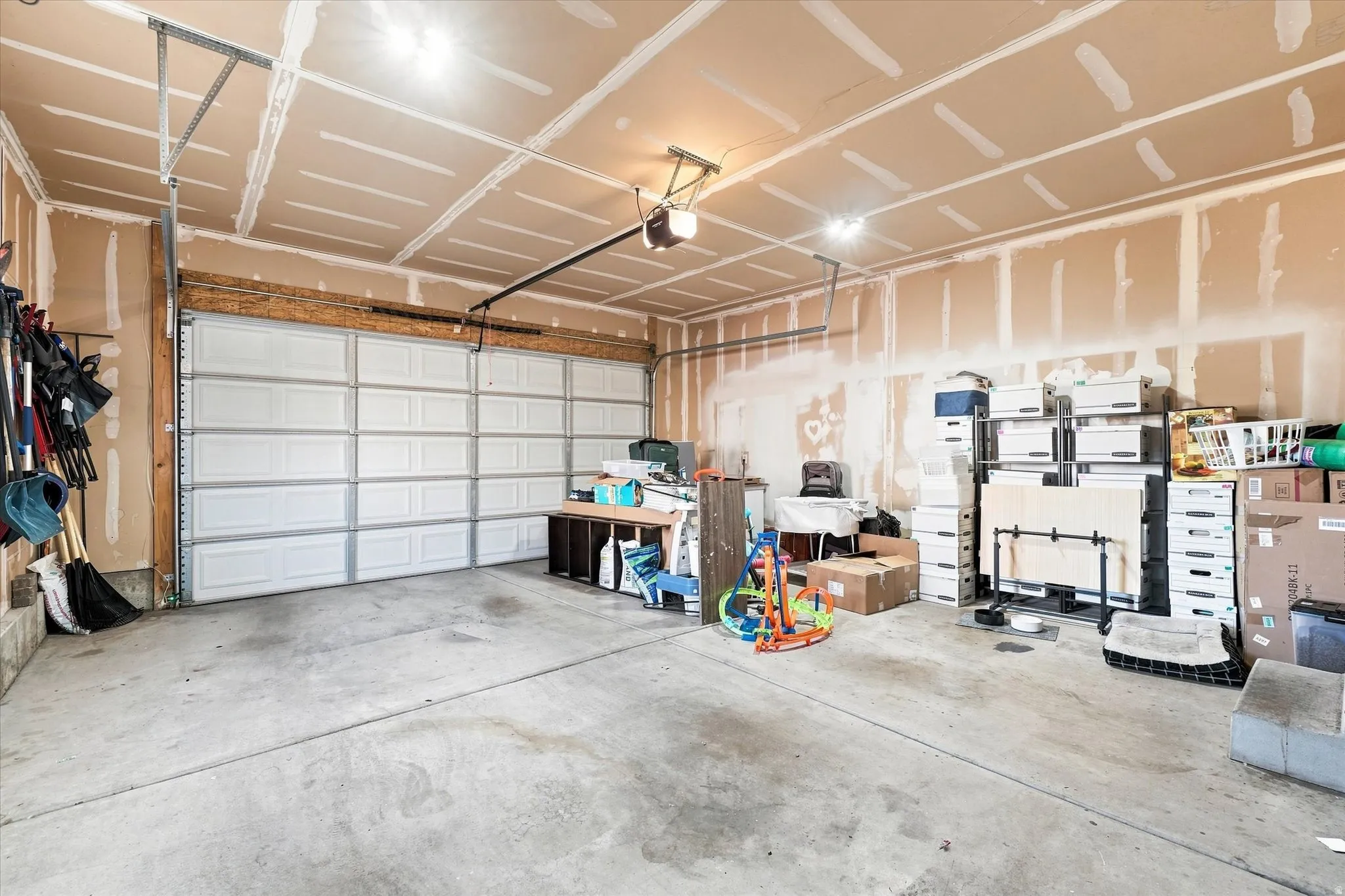 Concrete flooring garage with an automatic overhead door and exposed ceiling beams