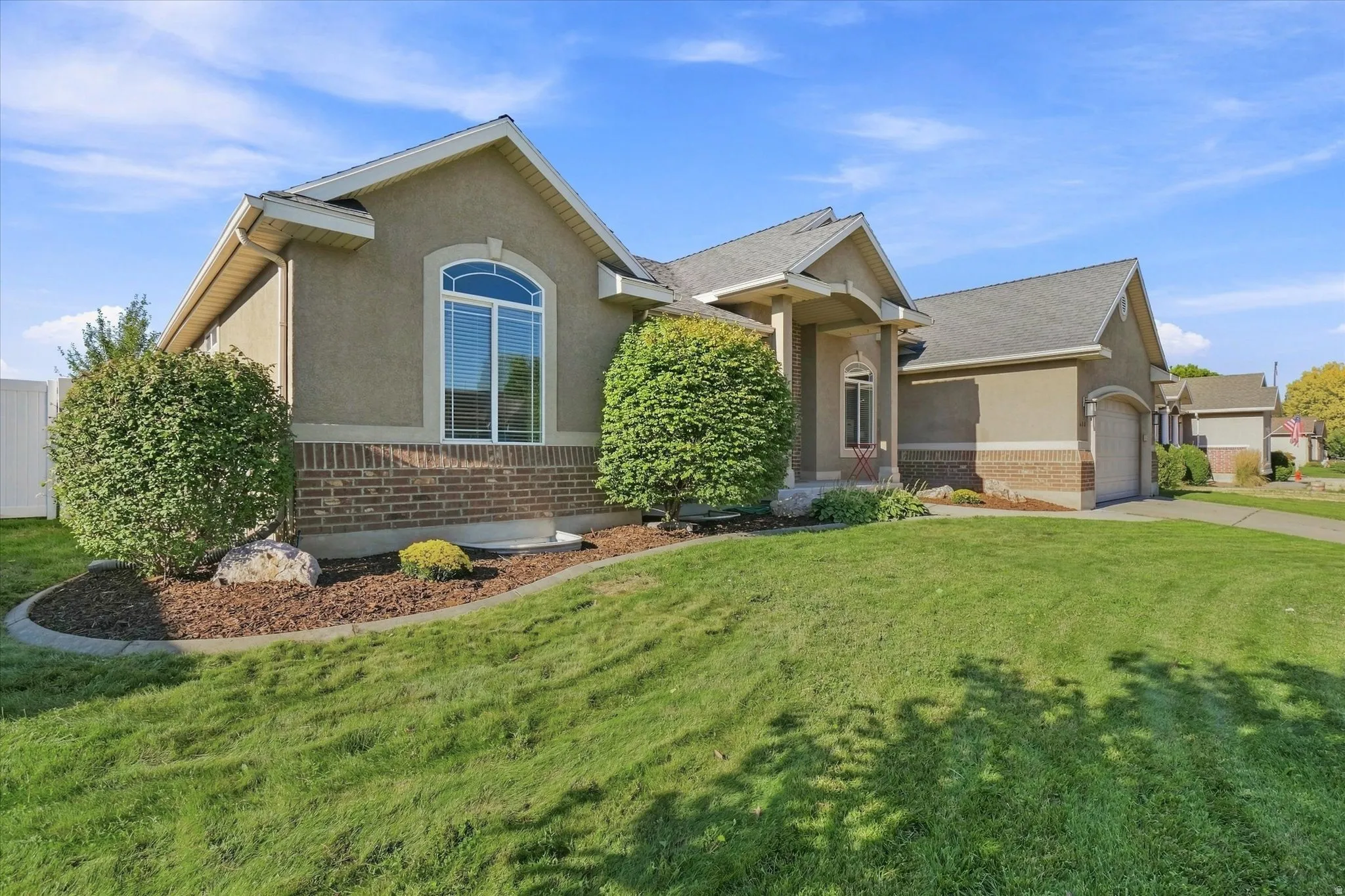 Stucco and brick exterior with arched window, covered entry, and attached garage