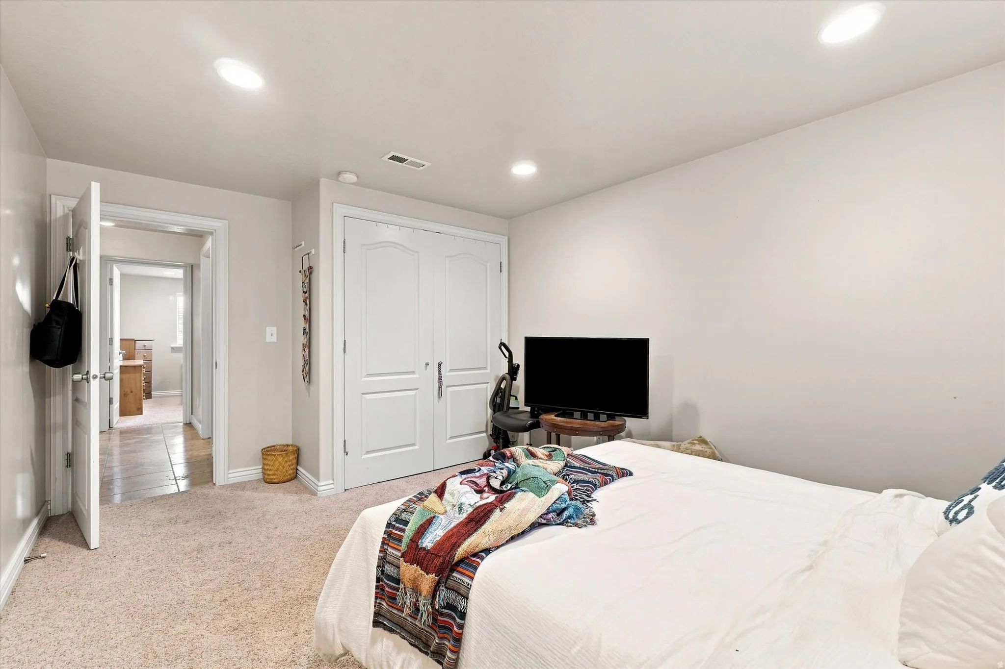 Recessed ceiling lighting, light-toned carpeting, and a double-door closet with arched paneling
