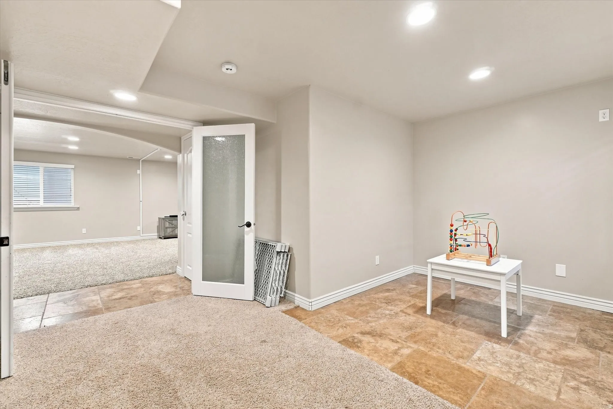 Recessed lighting, tile flooring, carpeted area, white interior door with frosted glass, and white window blinds