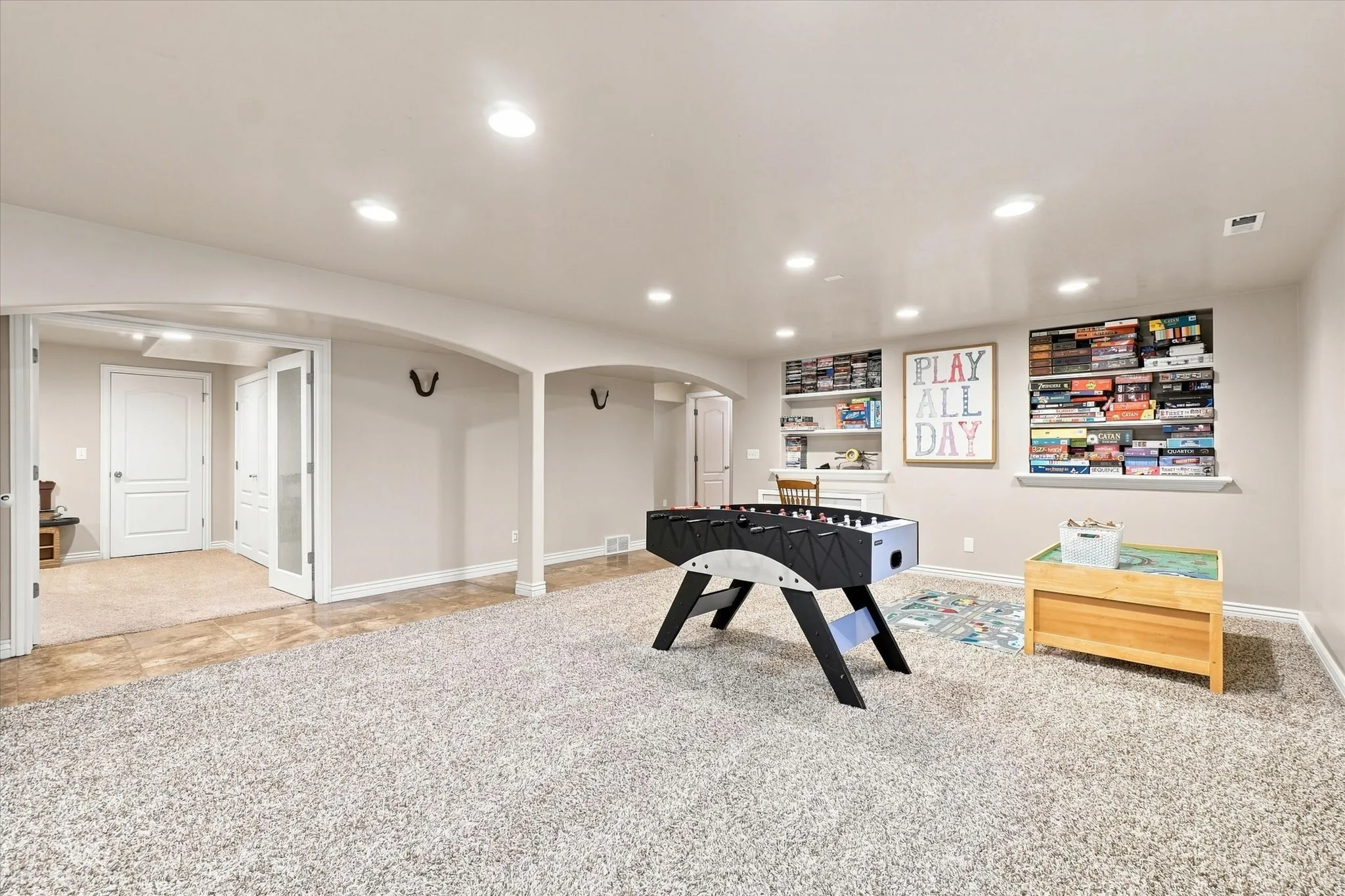 Recessed lighting, arched doorways, built-in shelving, and a combination of carpet and tile flooring