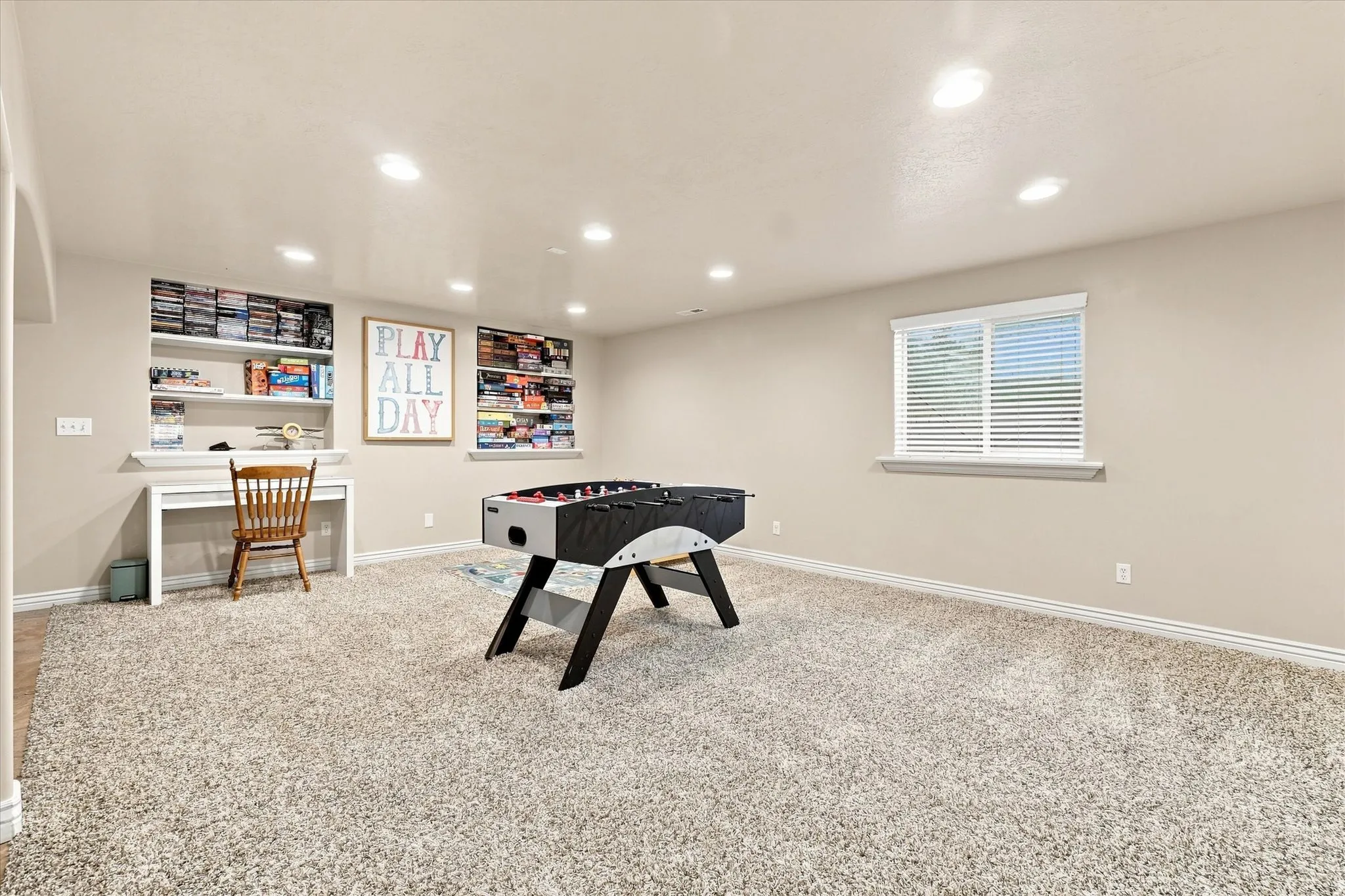 Recessed lighting, built-in shelving, window with blinds, and neutral carpet flooring