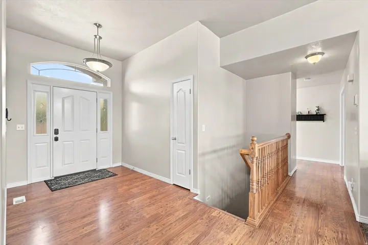 Entryway featuring wood-finish flooring, a white paneled front door with sidelights, and an arched transom window