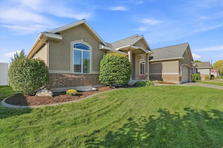 Stucco and brick exterior with arched window, covered entry, and attached garage
