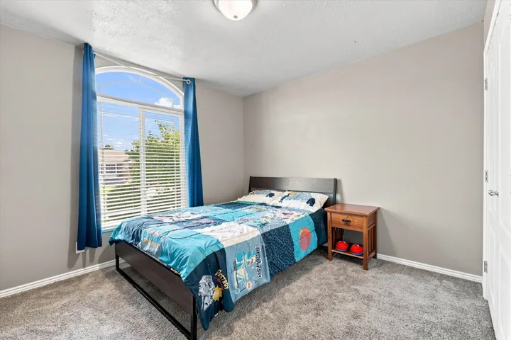 Arched window with blinds, carpeted flooring, neutral wall color, and a flush-mount ceiling light fixture