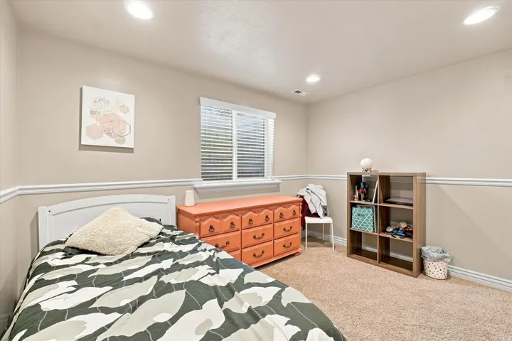 Recessed ceiling lighting, window with blinds, neutral wall paint, chair rail molding, and carpeted flooring