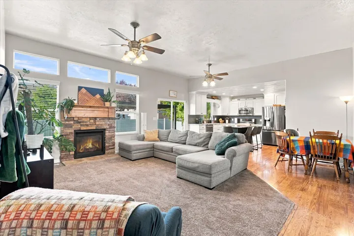 Open-concept living area featuring a stone-clad fireplace, wood mantel, and multiple transom windows