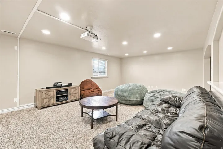 Recessed ceiling lighting, ceiling-mounted projector, wall-mounted projection screen, single window with blinds, light-toned carpeting