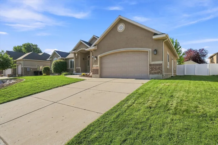Stucco exterior with brick detailing, an arched garage door, concrete driveway, and a white privacy fence