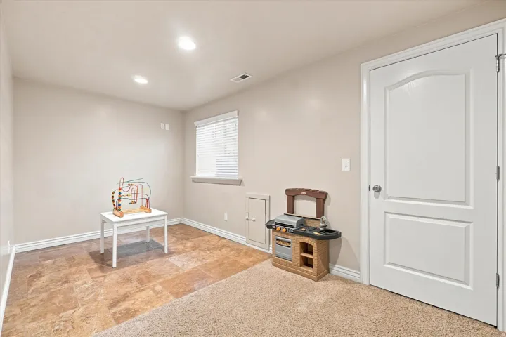 Recessed ceiling lighting, window with blinds, panel door, and dual-surface flooring with carpet and tile