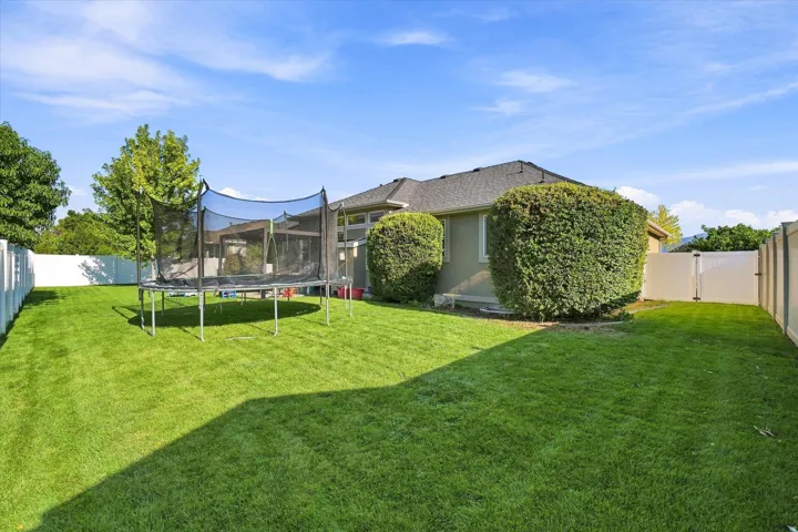 Expansive backyard featuring a manicured lawn, established shrubs, and durable privacy fencing