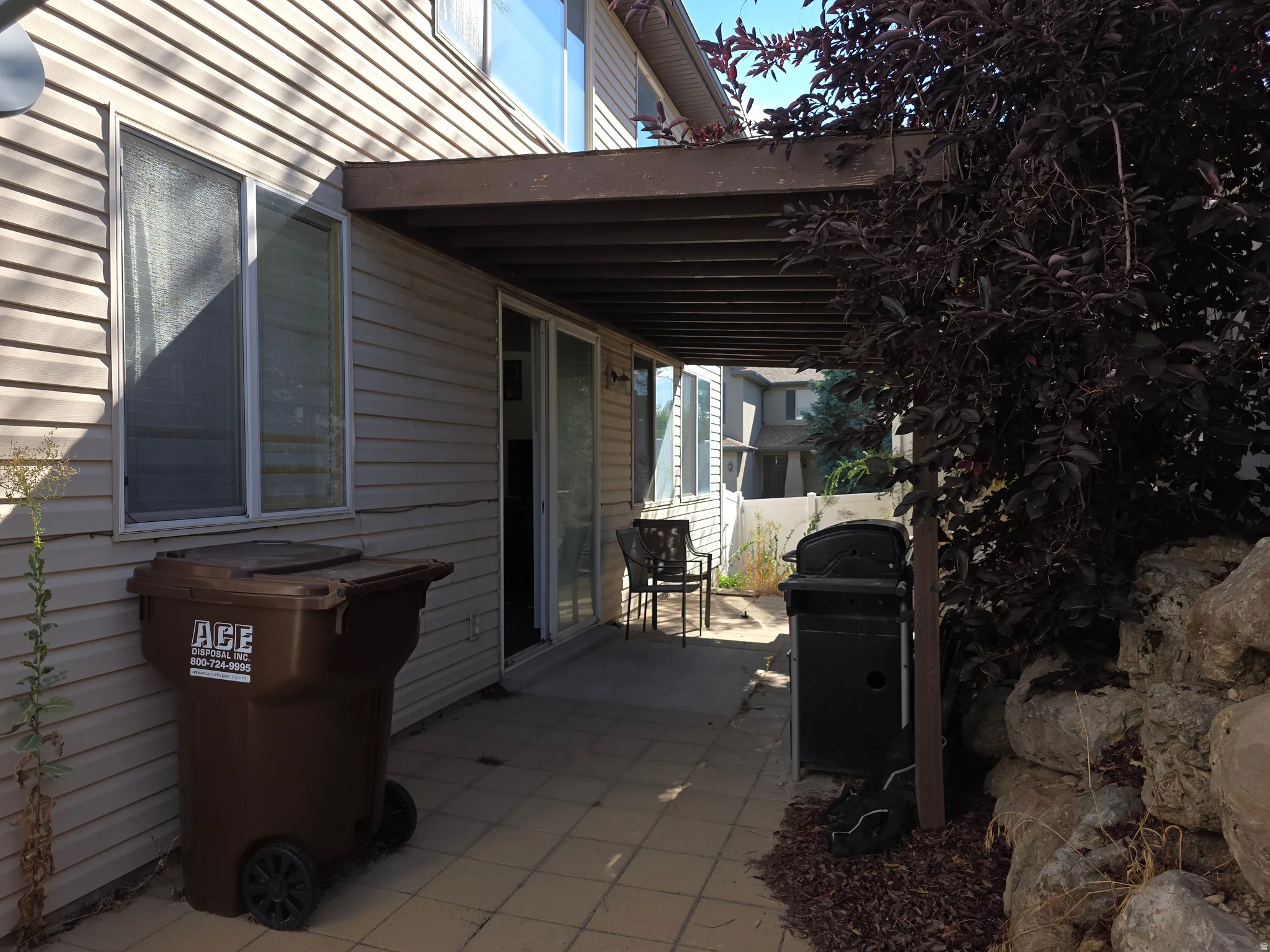 Patio with an overhead covering, sliding glass door, and a rock retaining wall