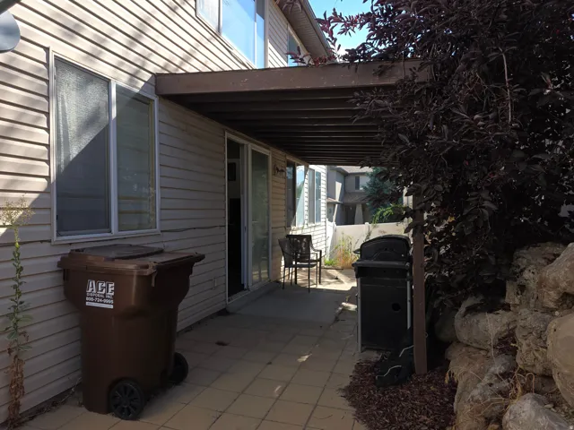 Patio with an overhead covering, sliding glass door, and a rock retaining wall