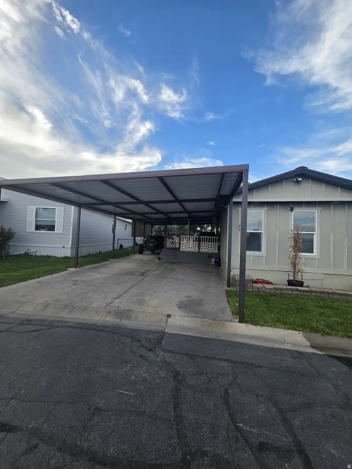 Extended carport structure with a concrete driveway and adjacent green space