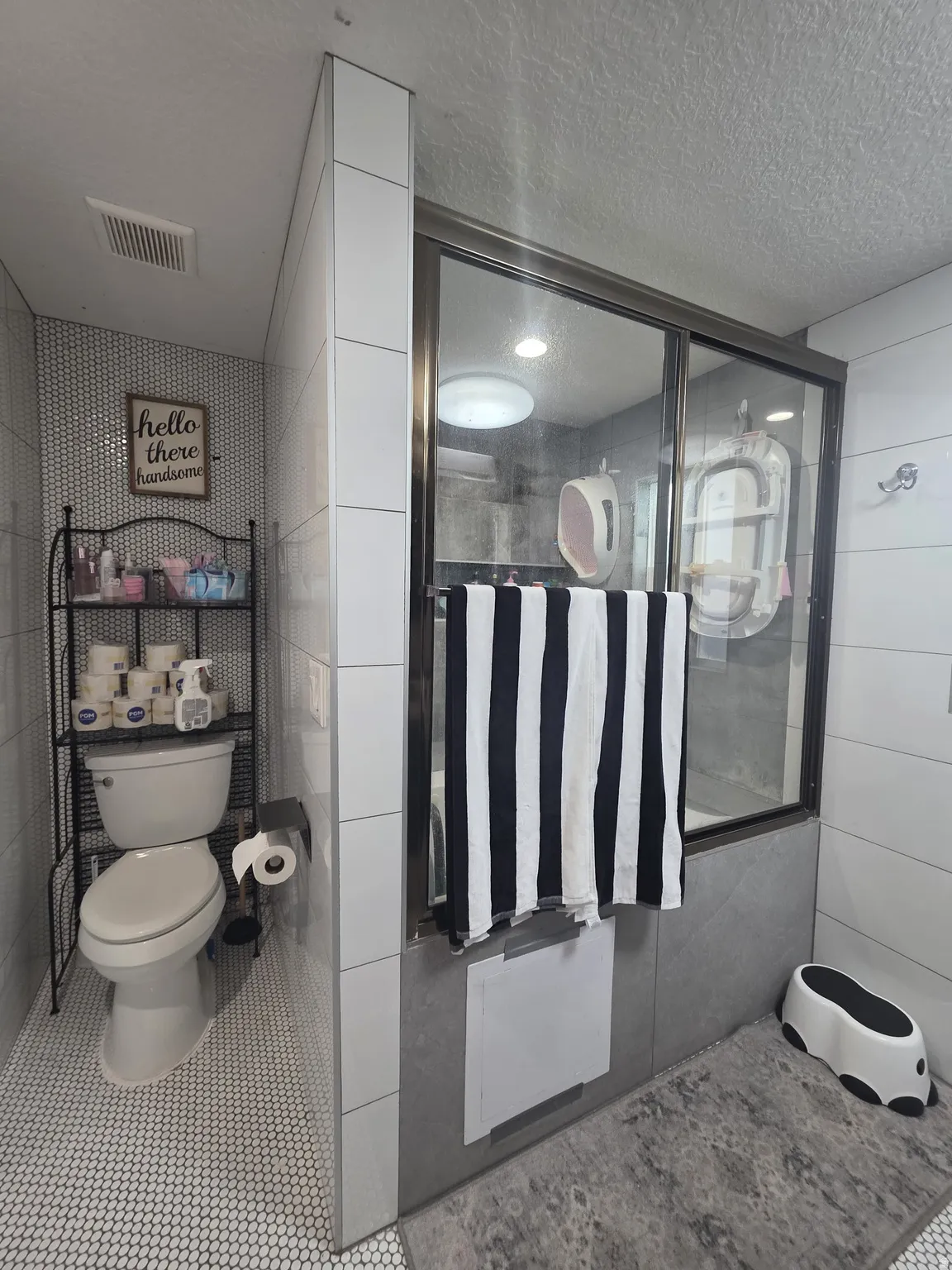 Shower enclosure with glass panels, white subway tile wall, and gray large format tile