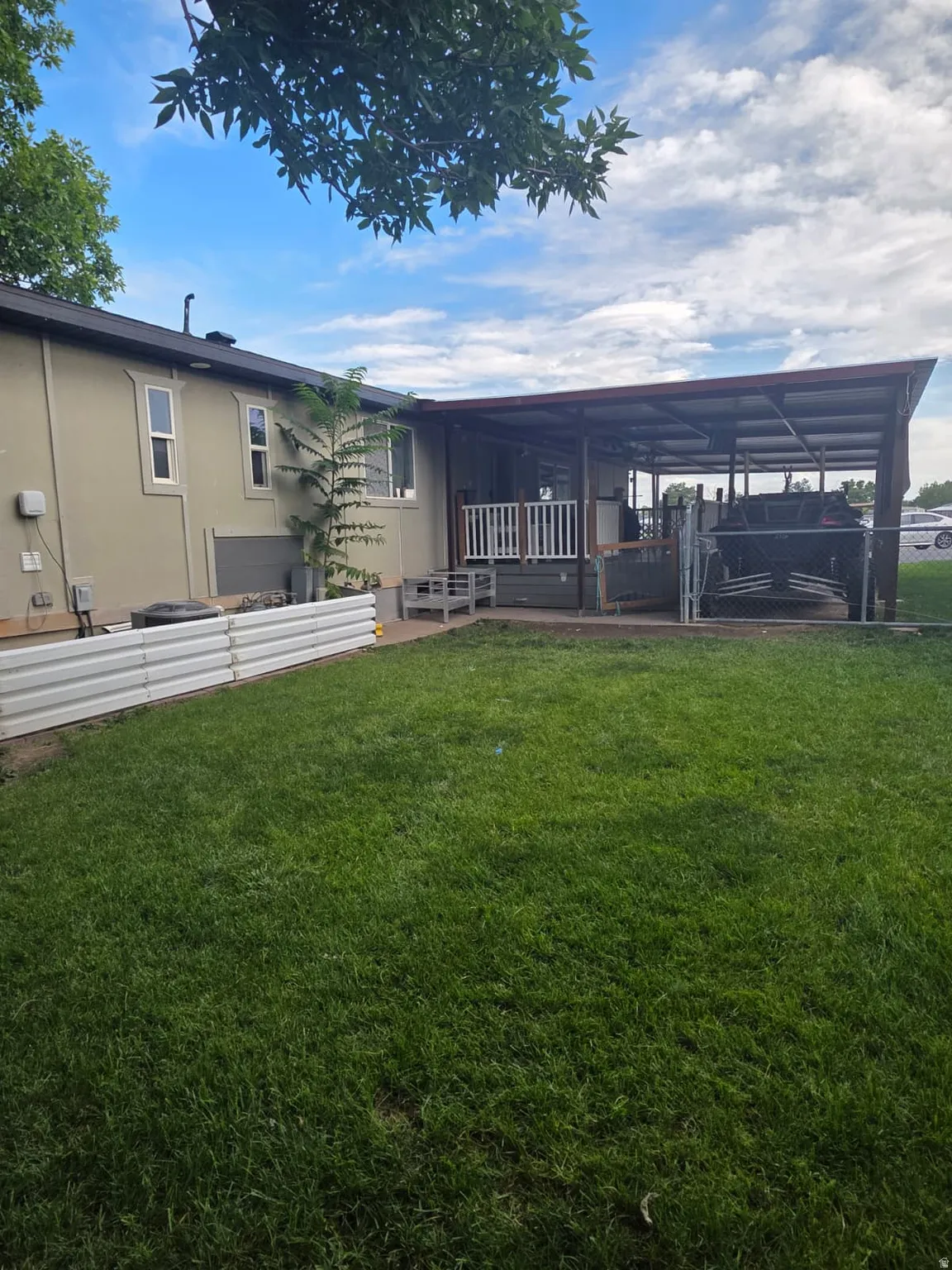 Expansive lawn area with a covered patio and white railing, featuring a neutral-toned exterior