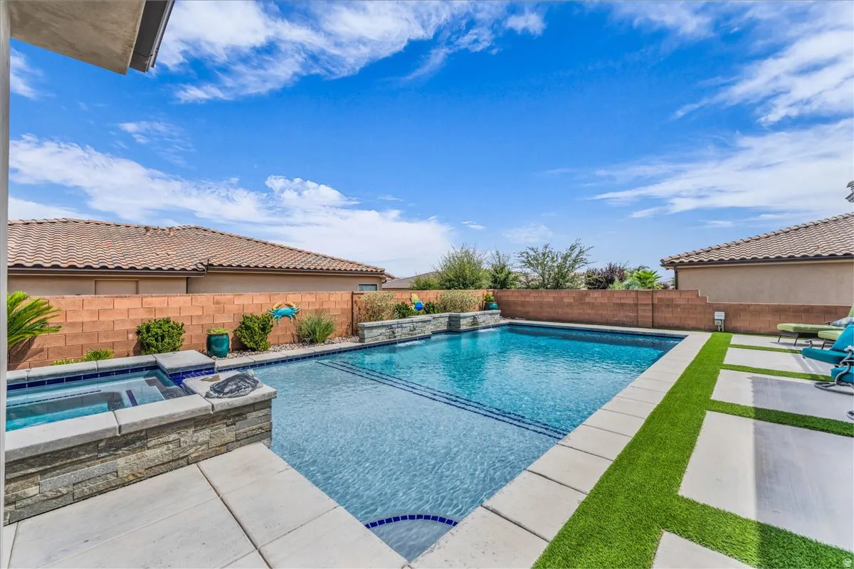 Backyard featuring an in-ground swimming pool, integrated spa, and artificial turf accents