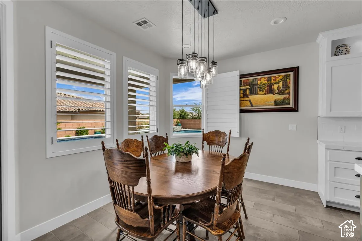 White plantation shutters, recessed lighting, and a modern multi-light pendant fixture