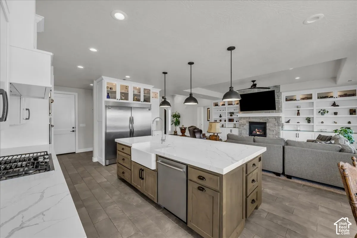 Kitchen island with a farmhouse sink, stainless steel appliances, and integrated shelving
