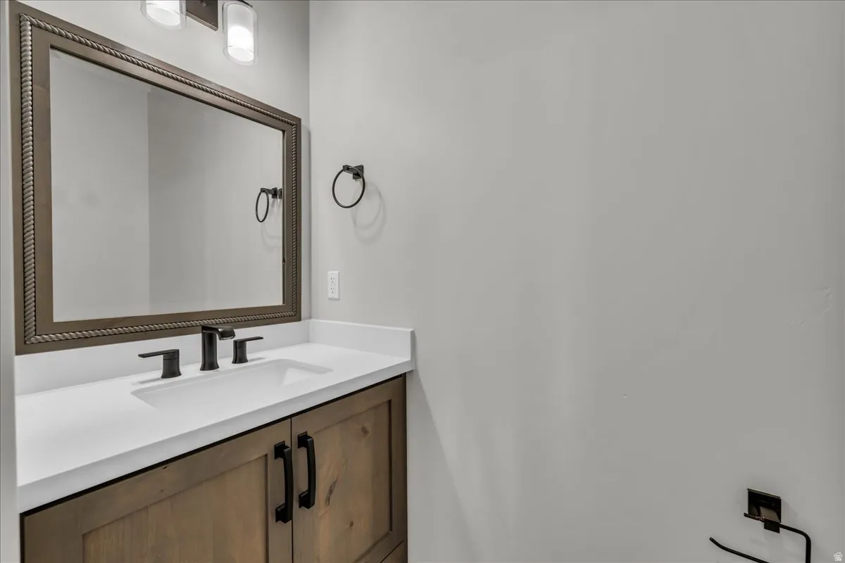Wood-finish vanity with matte black hardware, white countertop, integrated rectangular sink, and matte black faucet