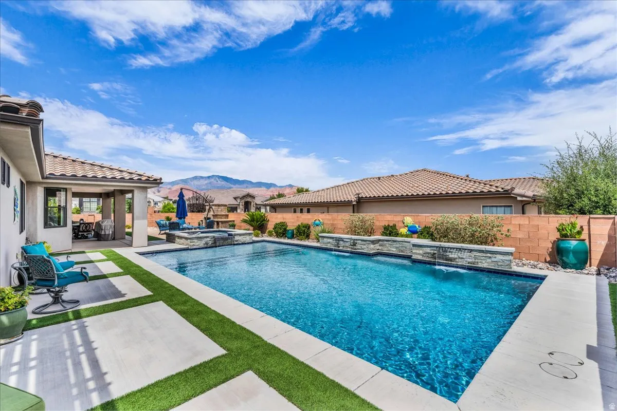 Private swimming pool with an integrated spa, stone-clad water features, and a covered patio area