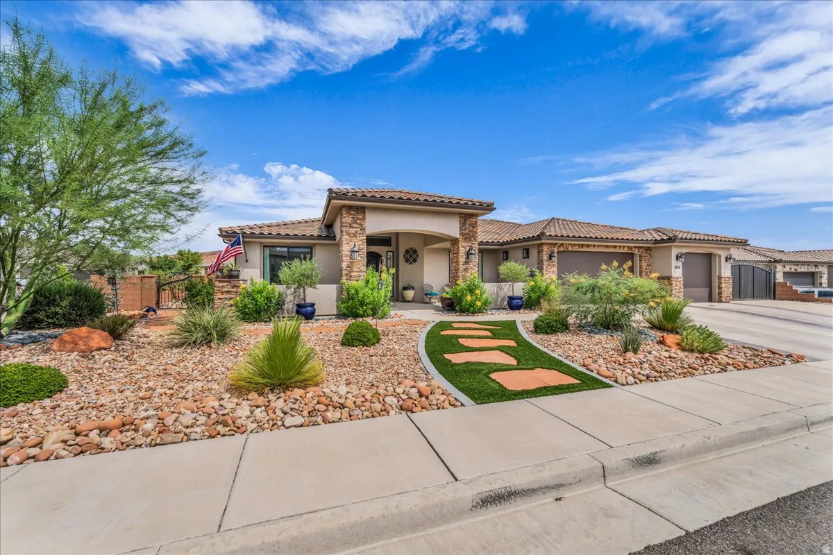 Mediterranean-style exterior with stone accents, tile roof, desert landscaping, and a paver pathway