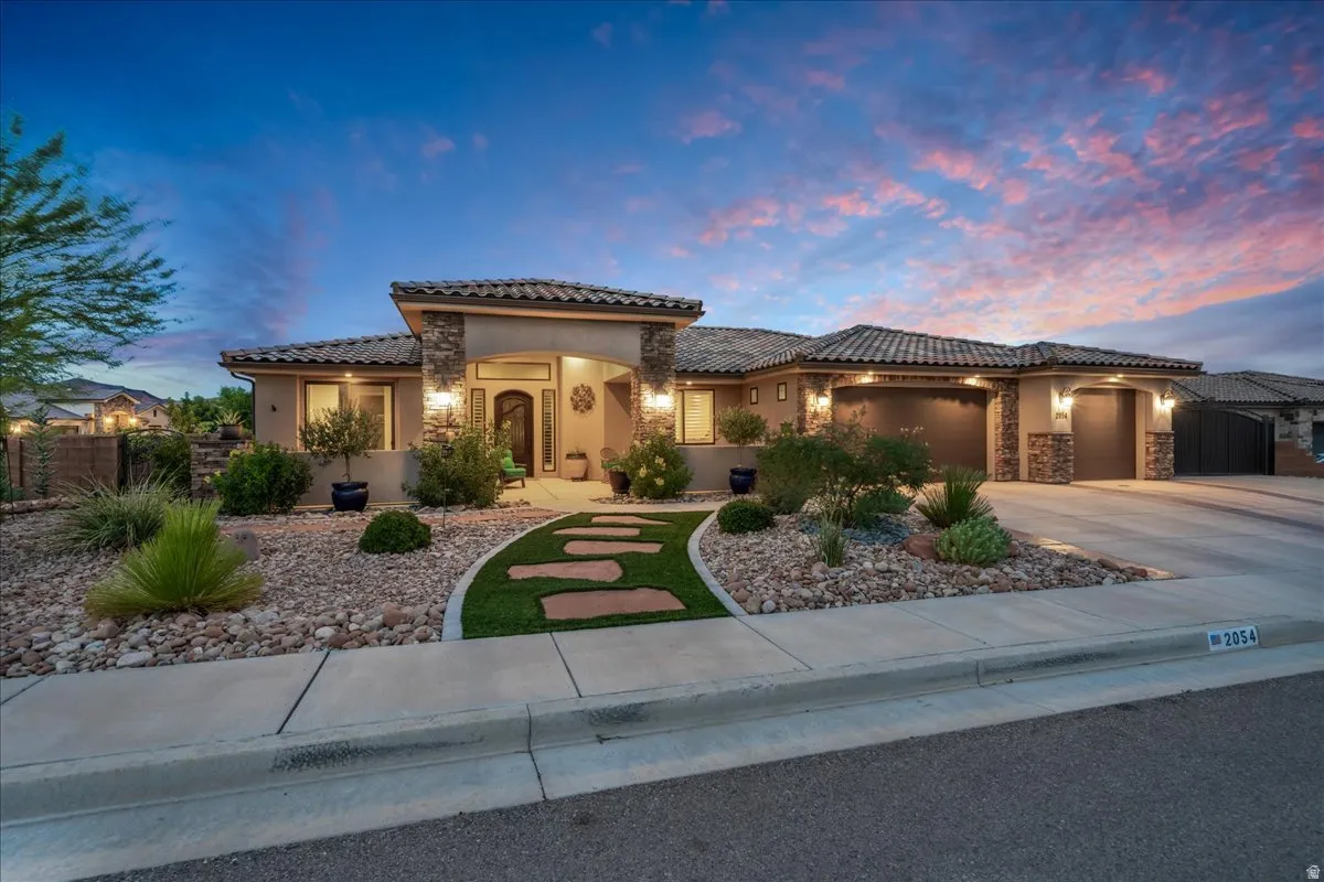 Stucco exterior with stone accents, tile roof, curved driveway, and a covered entry