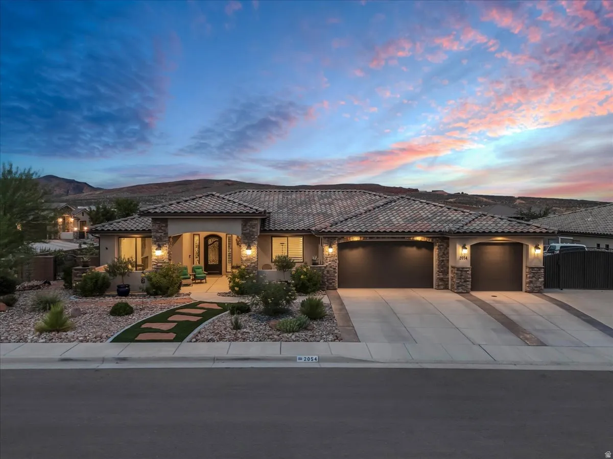 Elegant single-story residence showcasing a modern architectural design with a clay tile roof, stone and stucco exterior, and warm landscape lighting