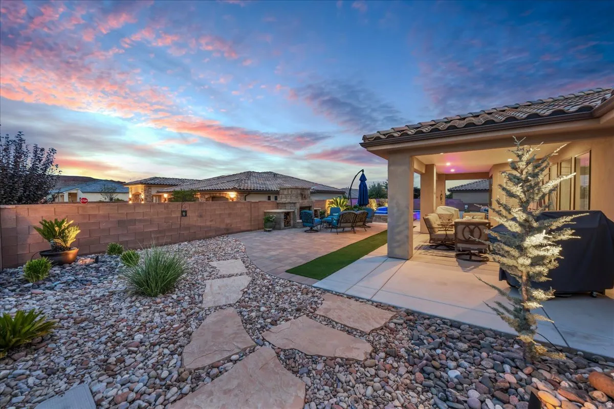 Covered patio with recessed lighting, paver patio, artificial turf accent, stone pathway, and xeriscape landscaping