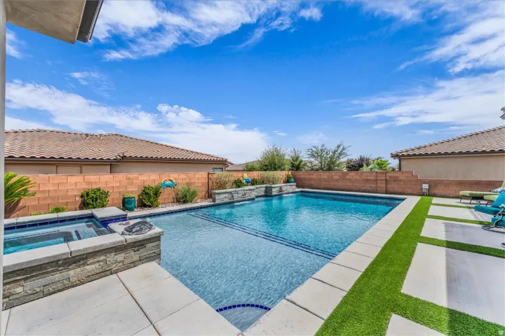 Backyard featuring an in-ground swimming pool, integrated spa, and artificial turf accents