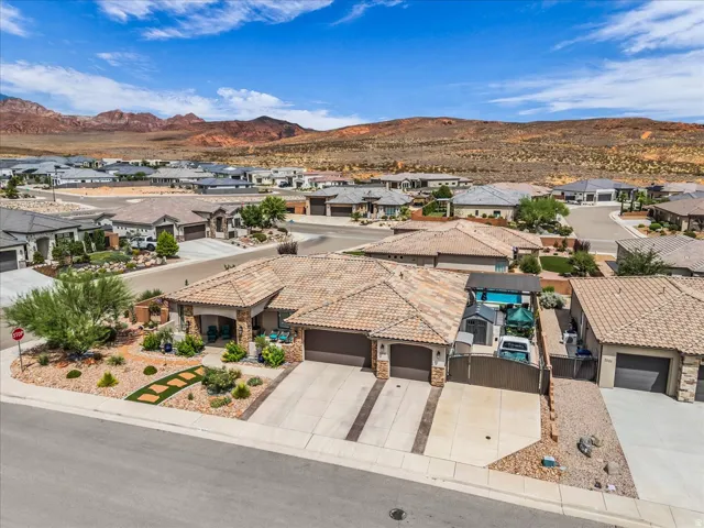 Terracotta tile roof with a desert landscape backdrop, featuring a covered patio, a swimming pool, and a two-car garage