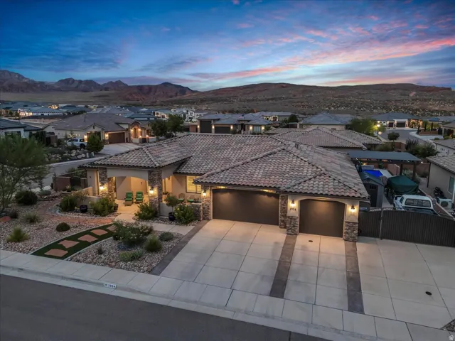 Tiled roof residence featuring an attached two-car garage, covered entry, and desert-inspired landscaping