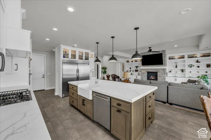 Kitchen island with a farmhouse sink, stainless steel appliances, and integrated shelving