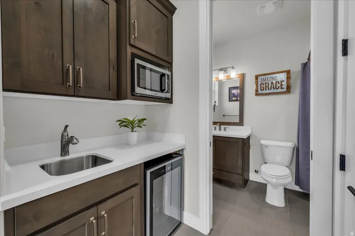 Wet bar with stainless steel sink, wood-finish cabinetry, and built-in microwave