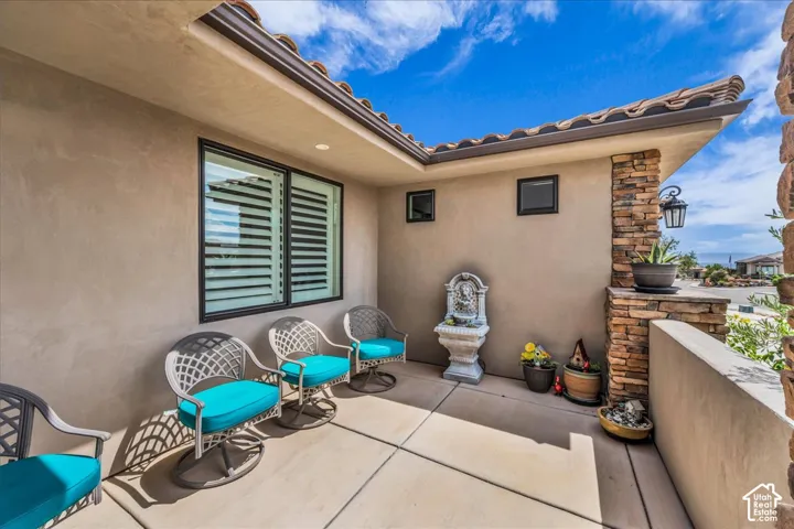 Entryway with stucco exterior, tiled roof, decorative stone column, and window with plantation shutters