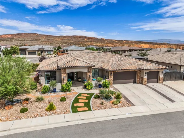 Single-story residence featuring a tile roof, stone accents, and an attached three-car garage