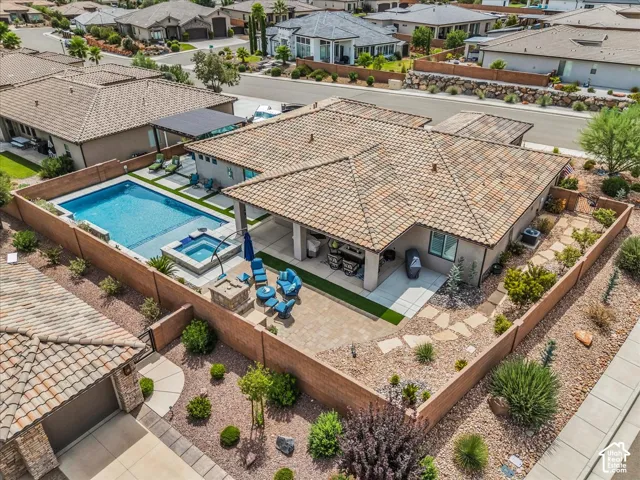 Private backyard featuring a swimming pool, integrated spa, covered patio, paver hardscaping, and xeriscape landscaping