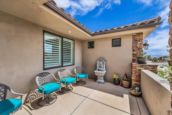 Entryway with stucco exterior, tiled roof, decorative stone column, and window with plantation shutters