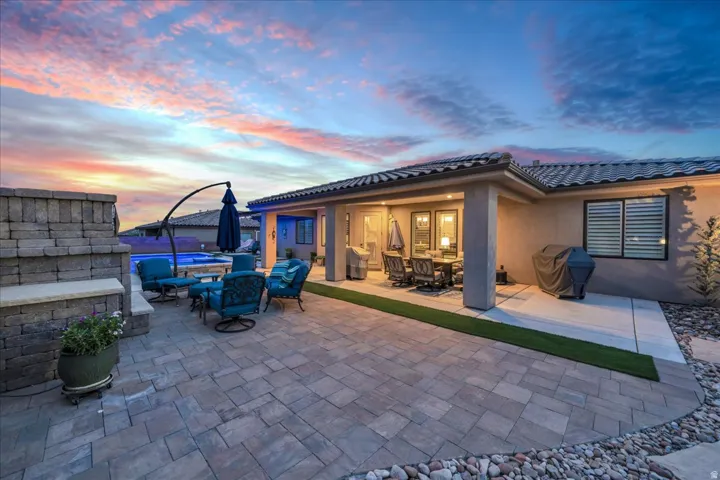 Paver patio with a built-in stone wall, covered outdoor dining area, and a swimming pool