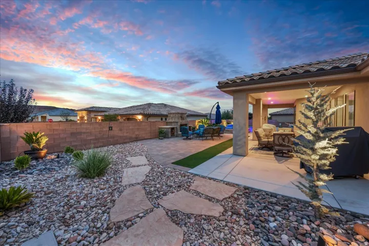 Covered patio with recessed lighting, paver patio, artificial turf accent, stone pathway, and xeriscape landscaping