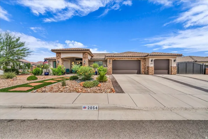 Stucco exterior with stone accents, covered entry, attached garage, and a concrete driveway