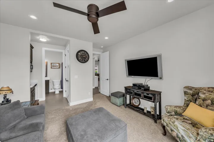 Recessed ceiling lighting, ceiling-mounted fan, mounted television, and a built-in wall niche with a floating vanity and sink