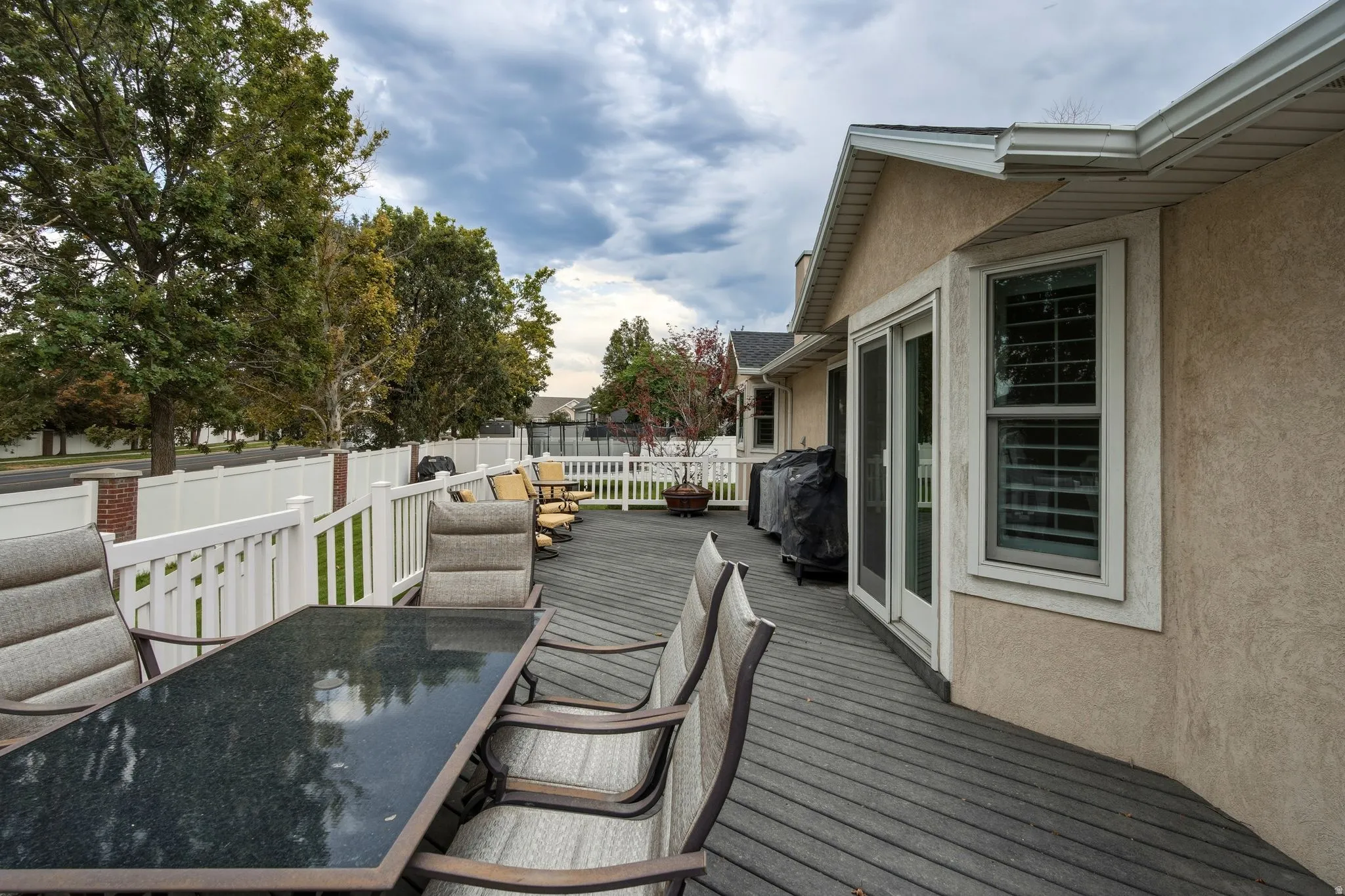 Expansive composite deck featuring composite decking with integrated dining and lounge areas, complemented by a white vinyl railing system