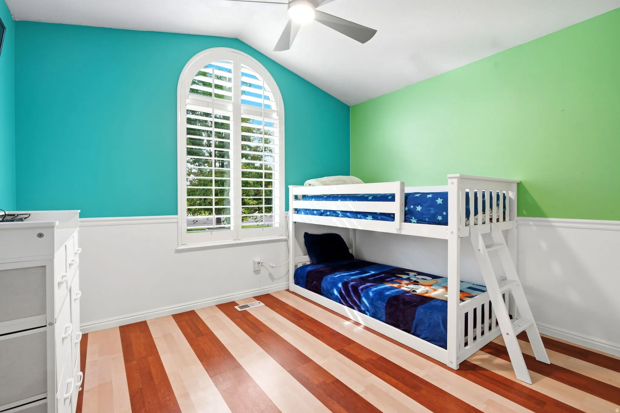 Bright and airy bedroom showcasing vibrant turquoise and lime green accent walls with crisp white wainscoting