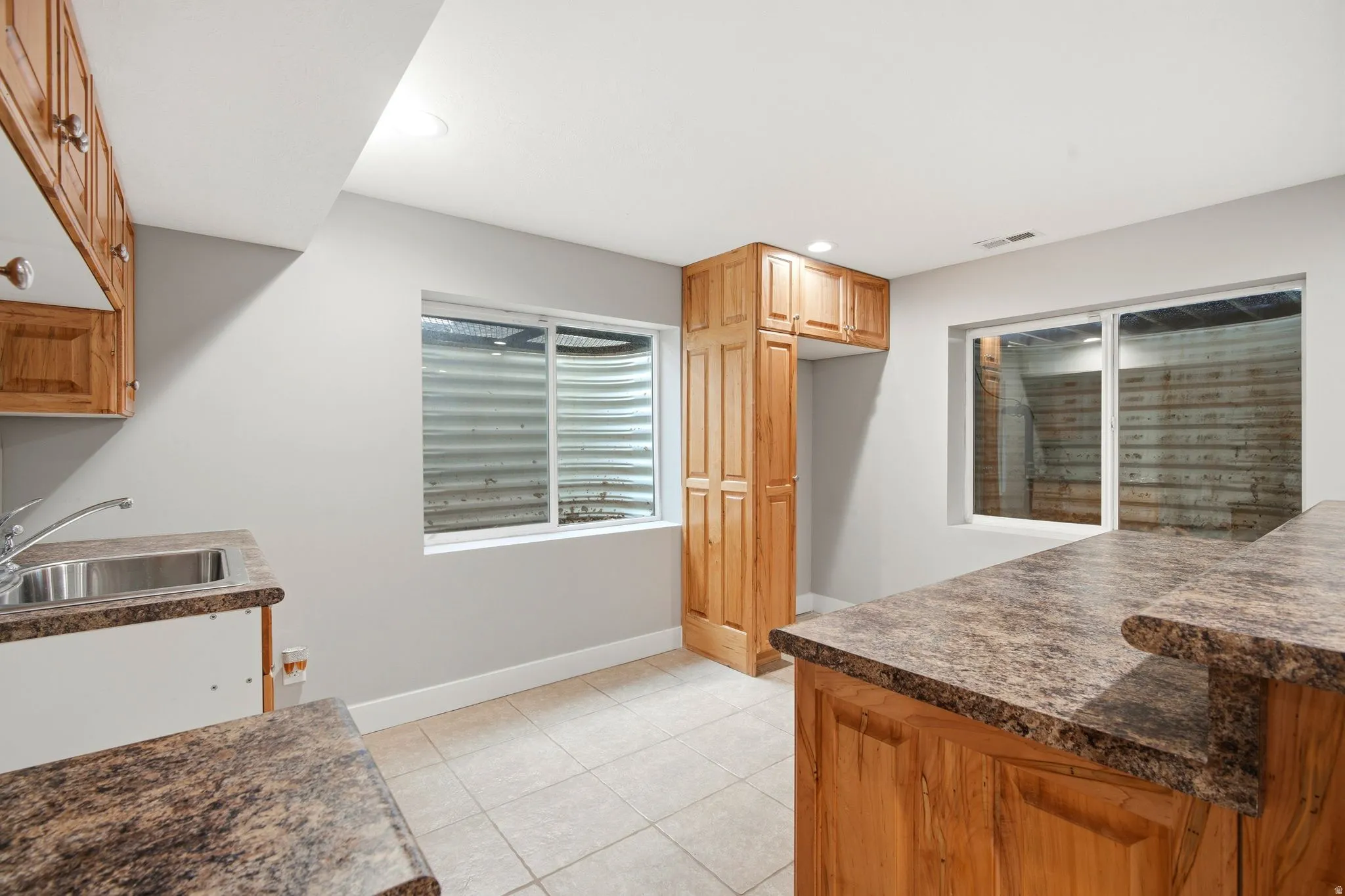 Recessed lighting illuminates wood-finish cabinetry, a stainless steel sink, and durable laminate countertops