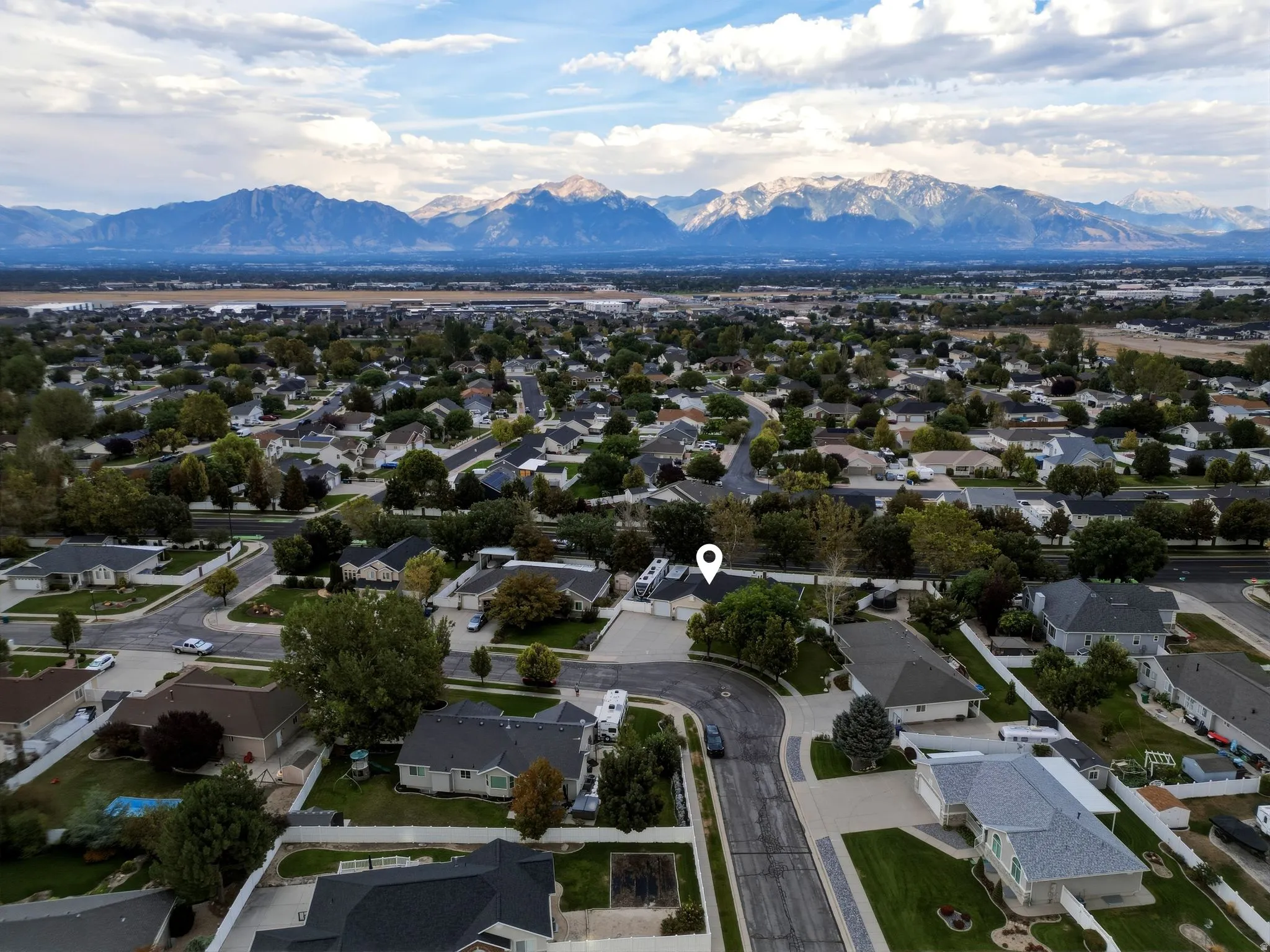 Aerial perspective showcasing a well-established residential neighborhood with mature landscaping, tree-lined streets, and proximity to expansive mountain ranges