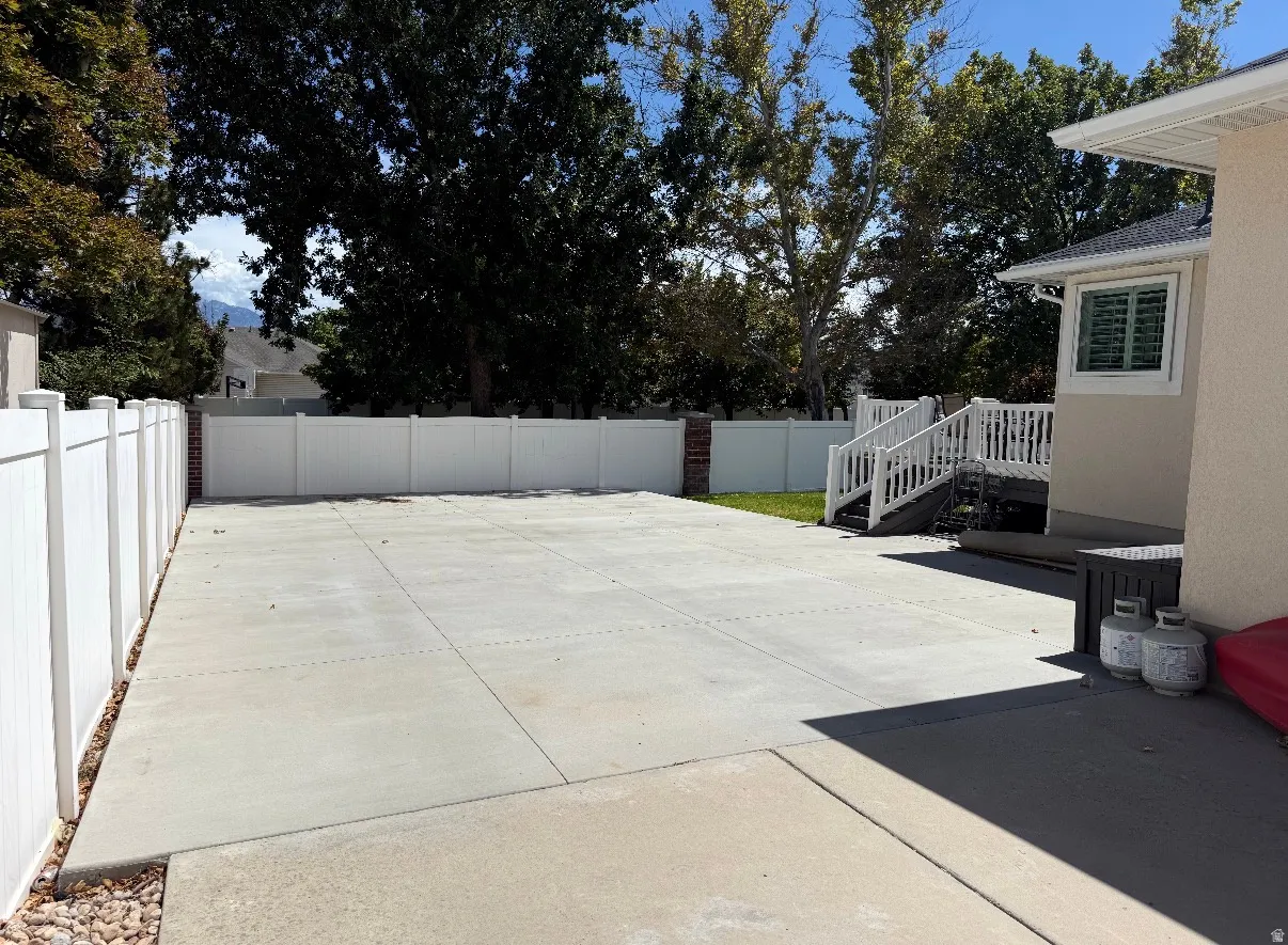 Expansive concrete patio with clean sight lines and professional finishing, bordered by white vinyl fencing