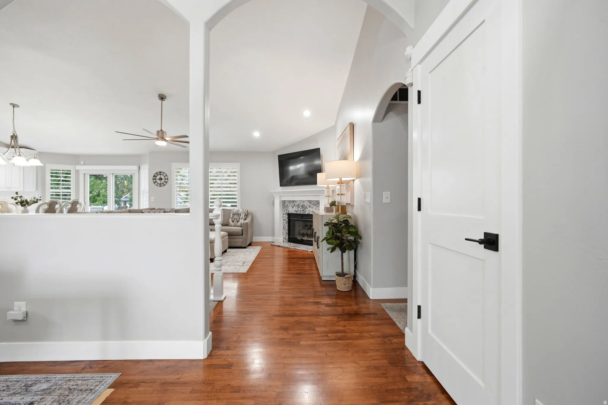 Elegant foyer with soaring vaulted ceilings and recessed lighting, featuring warm wood-finish flooring and white shaker-style doors